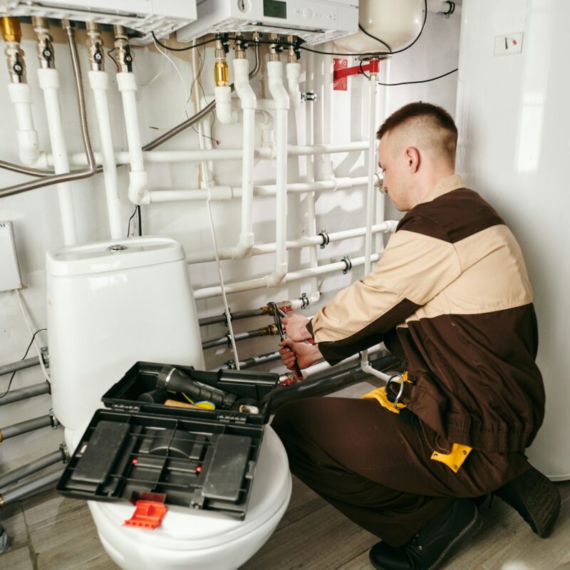 young-male-worker-in-uniform-repairing-pipes-in-lavatory